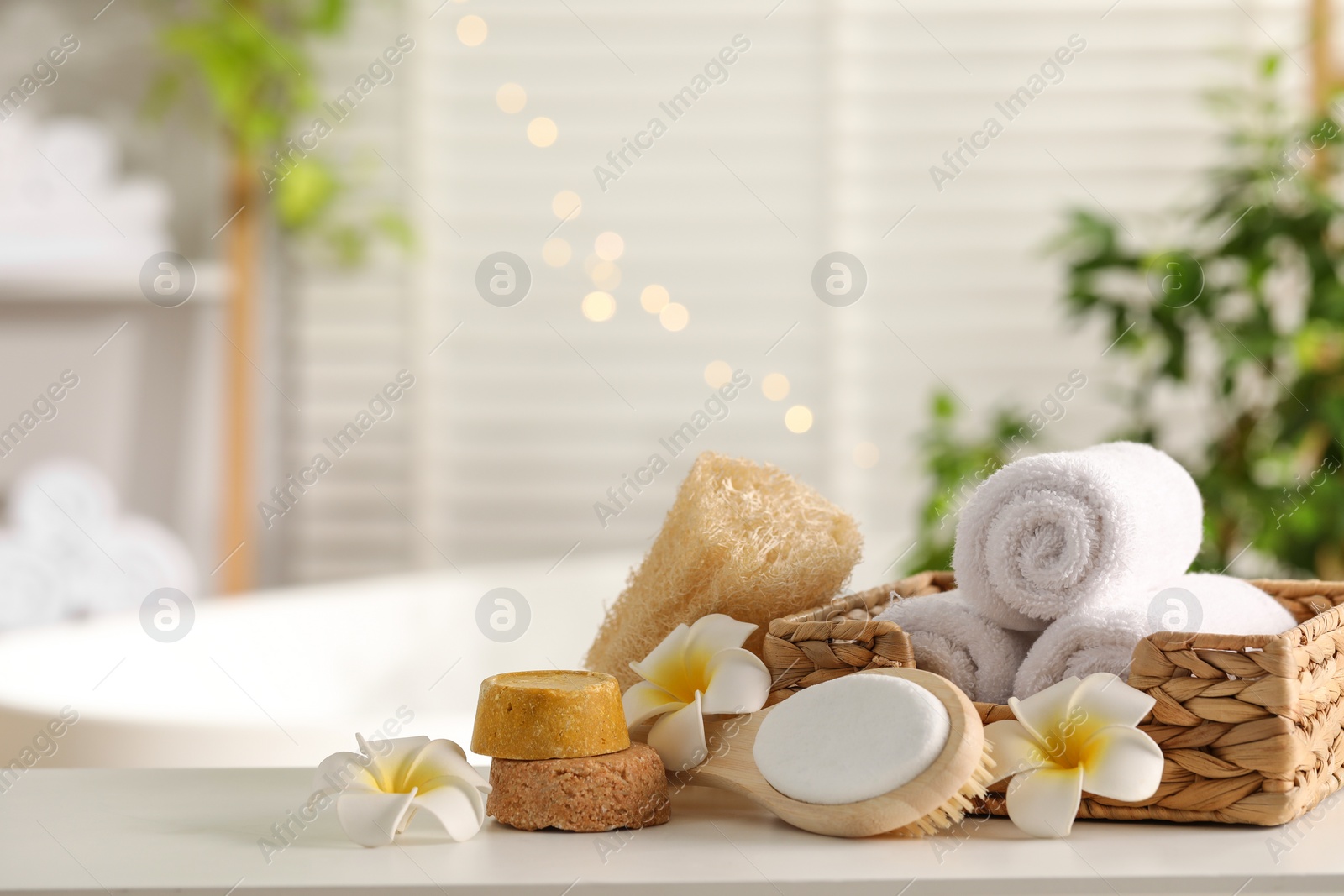 Photo of Composition with different spa products and plumeria flowers on white table in bathroom. Space for text