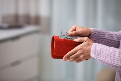 Woman with American money in wallet indoors, closeup. Space for text