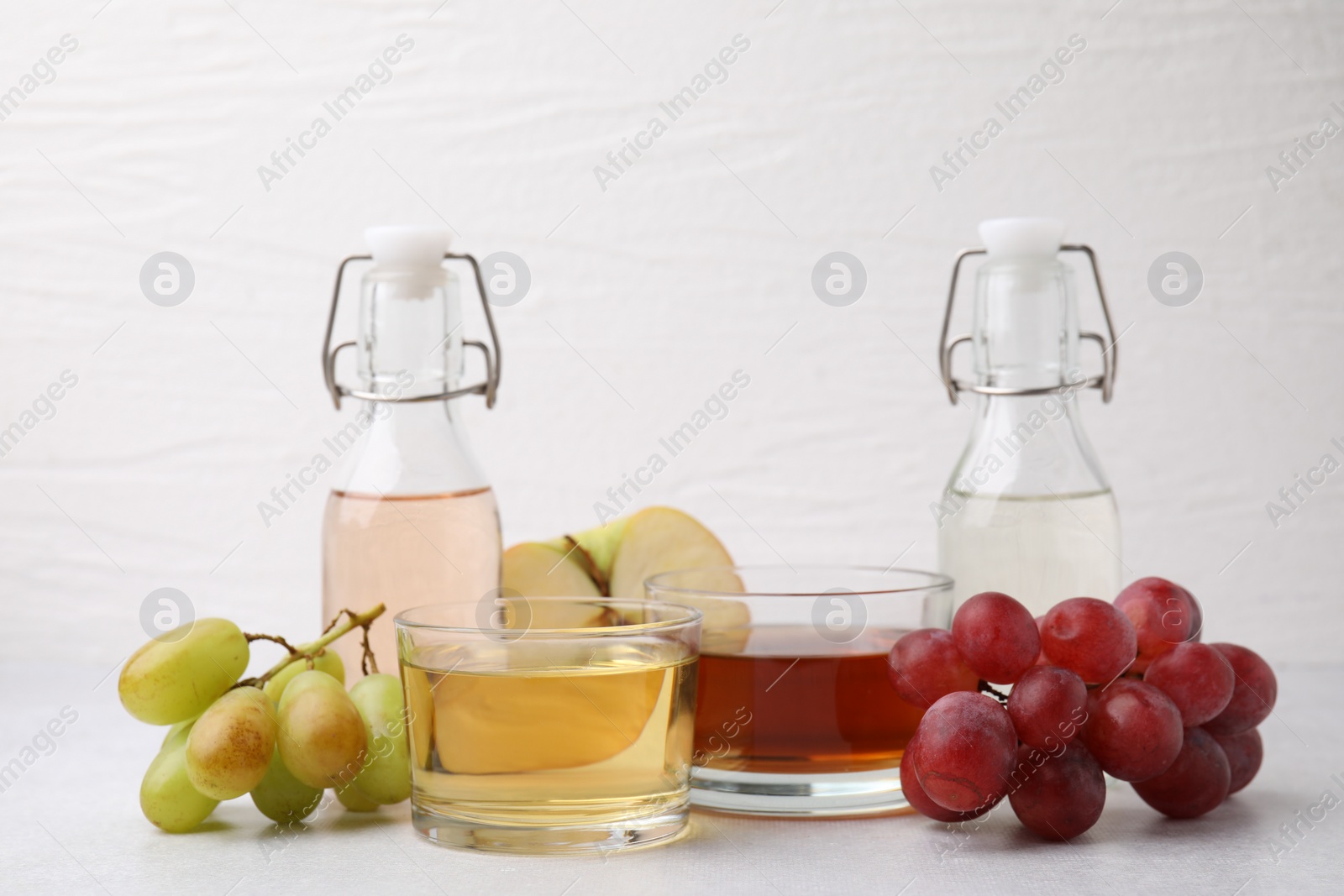 Photo of Different types of vinegar and ingredients on light table, closeup