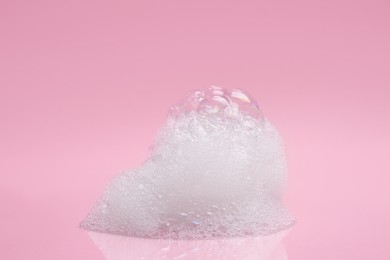 Photo of Drop of fluffy bath foam on pink background