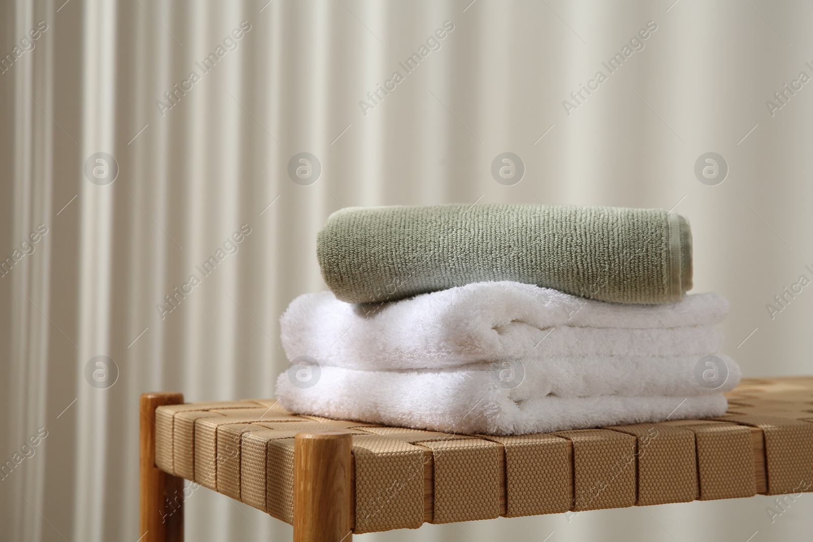 Photo of Soft towels on wicker bench indoors, space for text