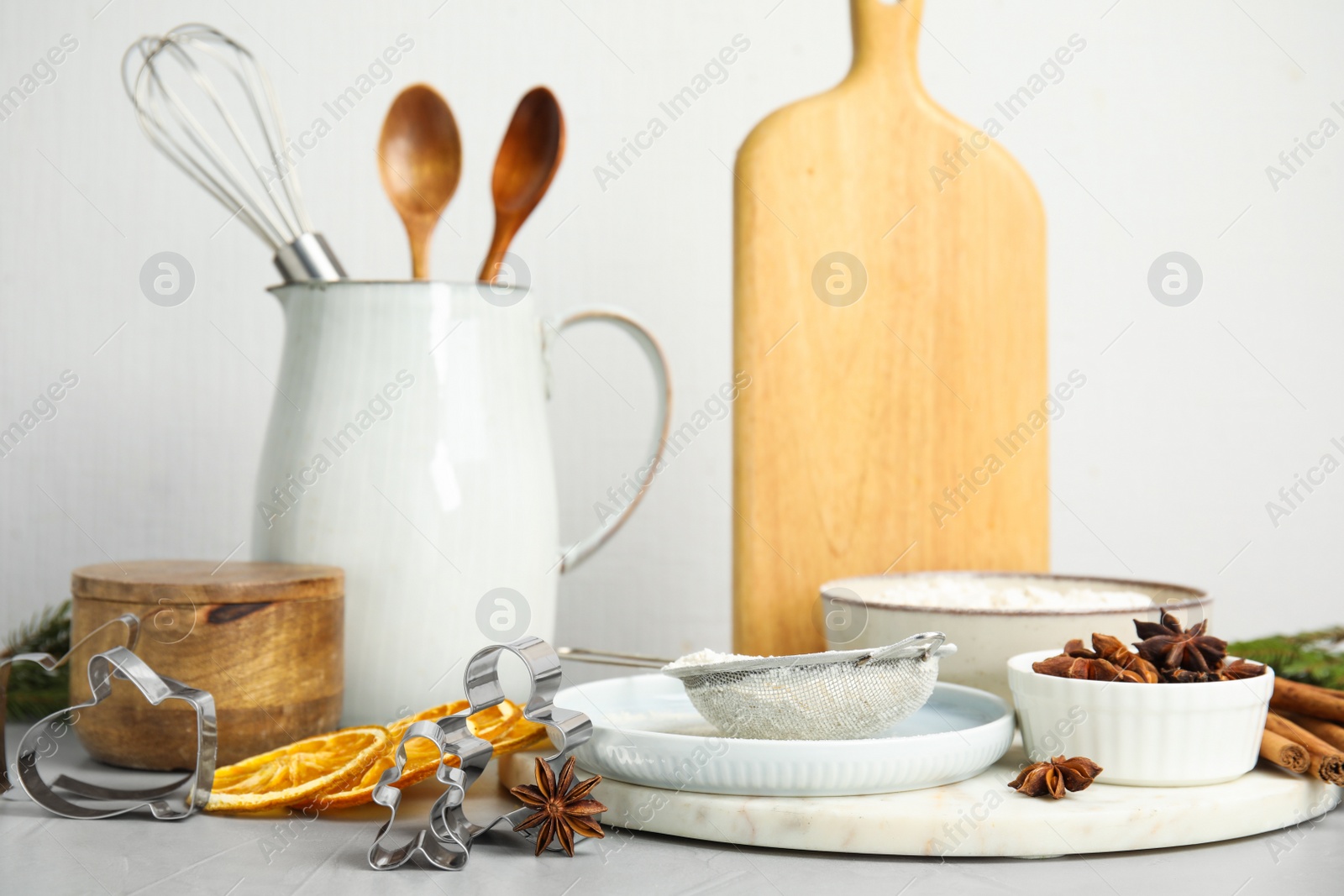 Photo of Cookie cutters, ingredients and crockery on white table. Christmas biscuits