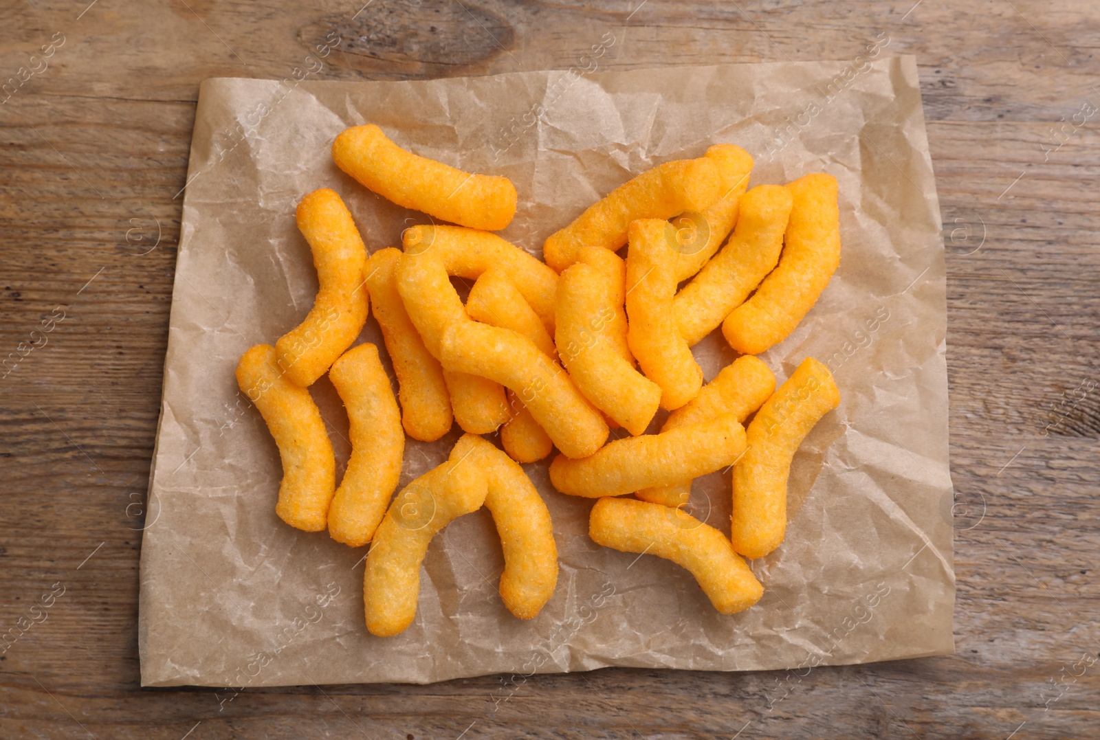 Photo of Many tasty cheesy corn puffs on wooden table, top view