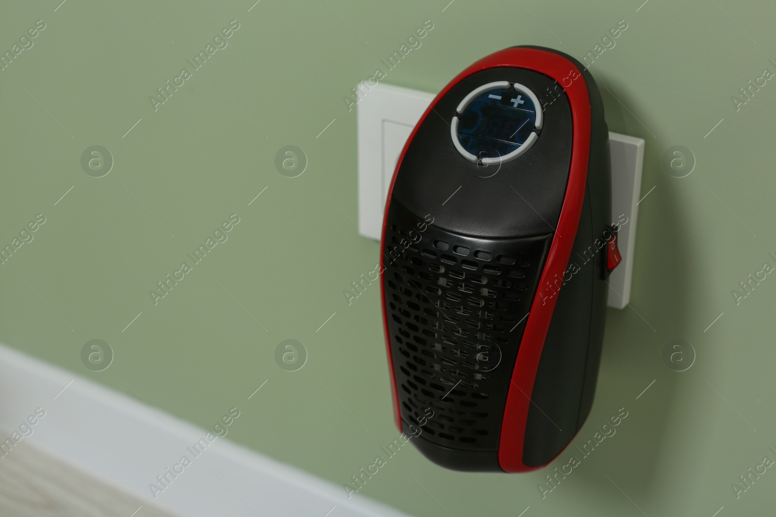 Photo of Portable electric heater on pale green wall indoors. Space for text