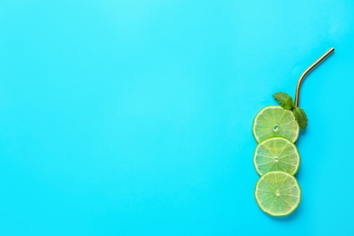 Photo of Creative image of summer cocktail made with lime slices, mint and straw on color background, top view. Space for text