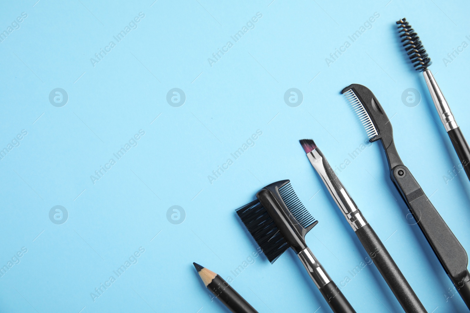 Photo of Set of professional eyebrow tools on blue background, flat lay. Space for text