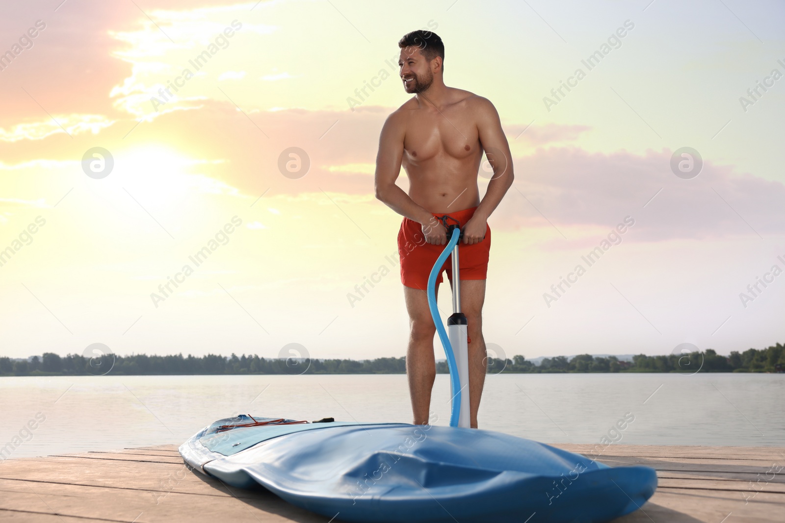 Photo of Man pumping up SUP board on pier