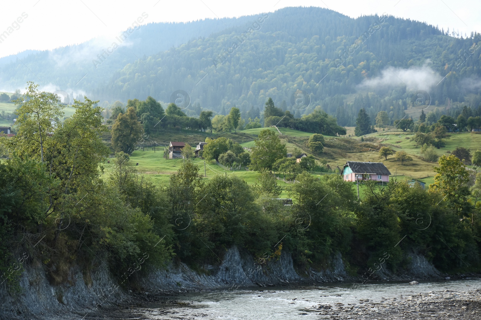 Photo of Picturesque view of mountain forest and village in foggy morning