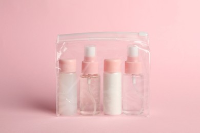 Cosmetic travel kit in plastic bag on pink background