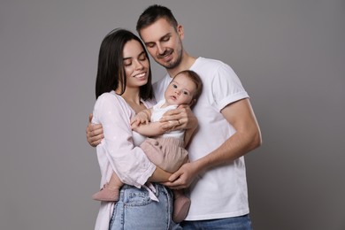 Photo of Happy family. Couple with their cute baby on grey background