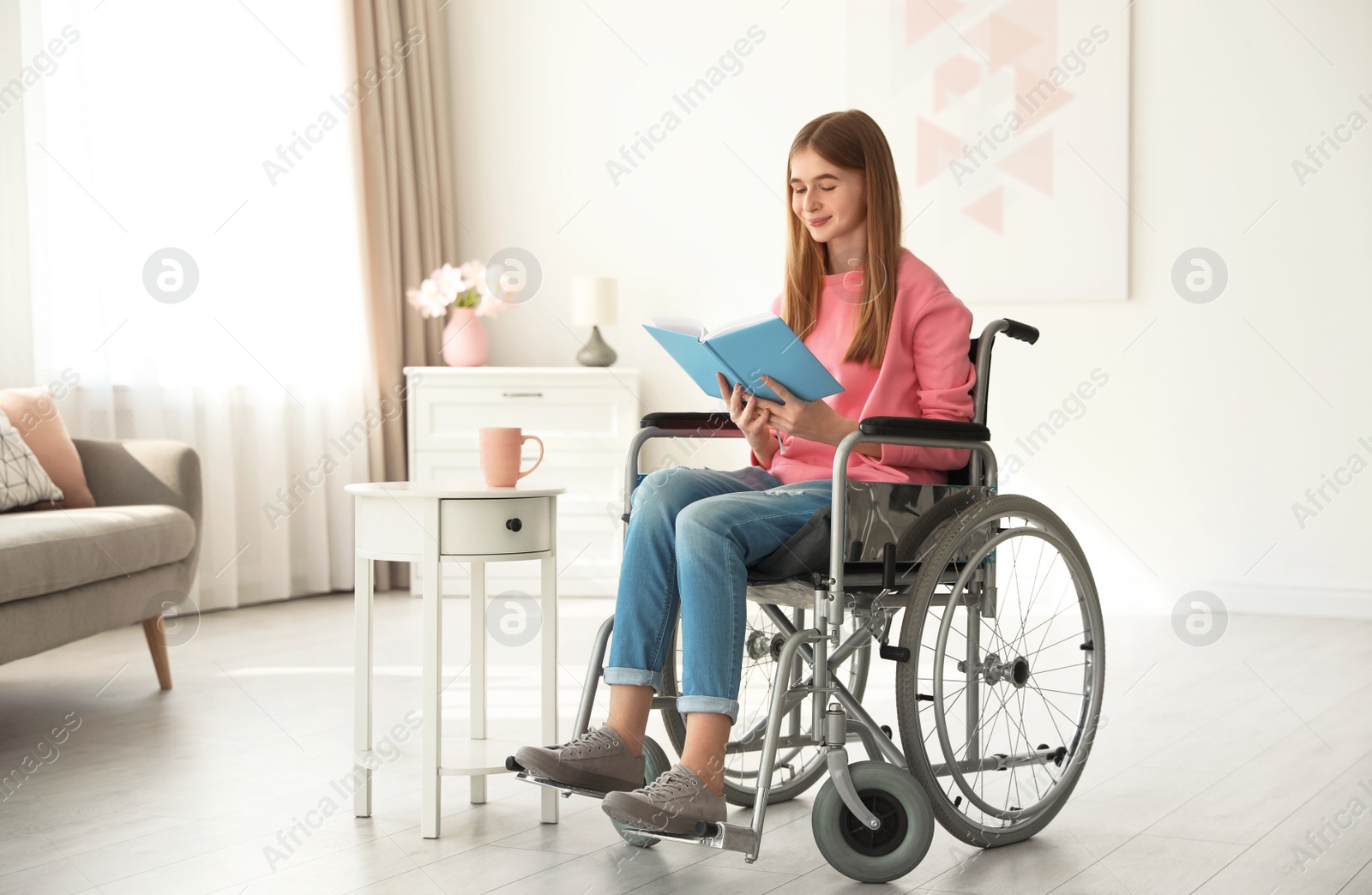 Photo of Teenage girl with book in wheelchair at home