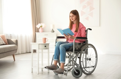 Teenage girl with book in wheelchair at home