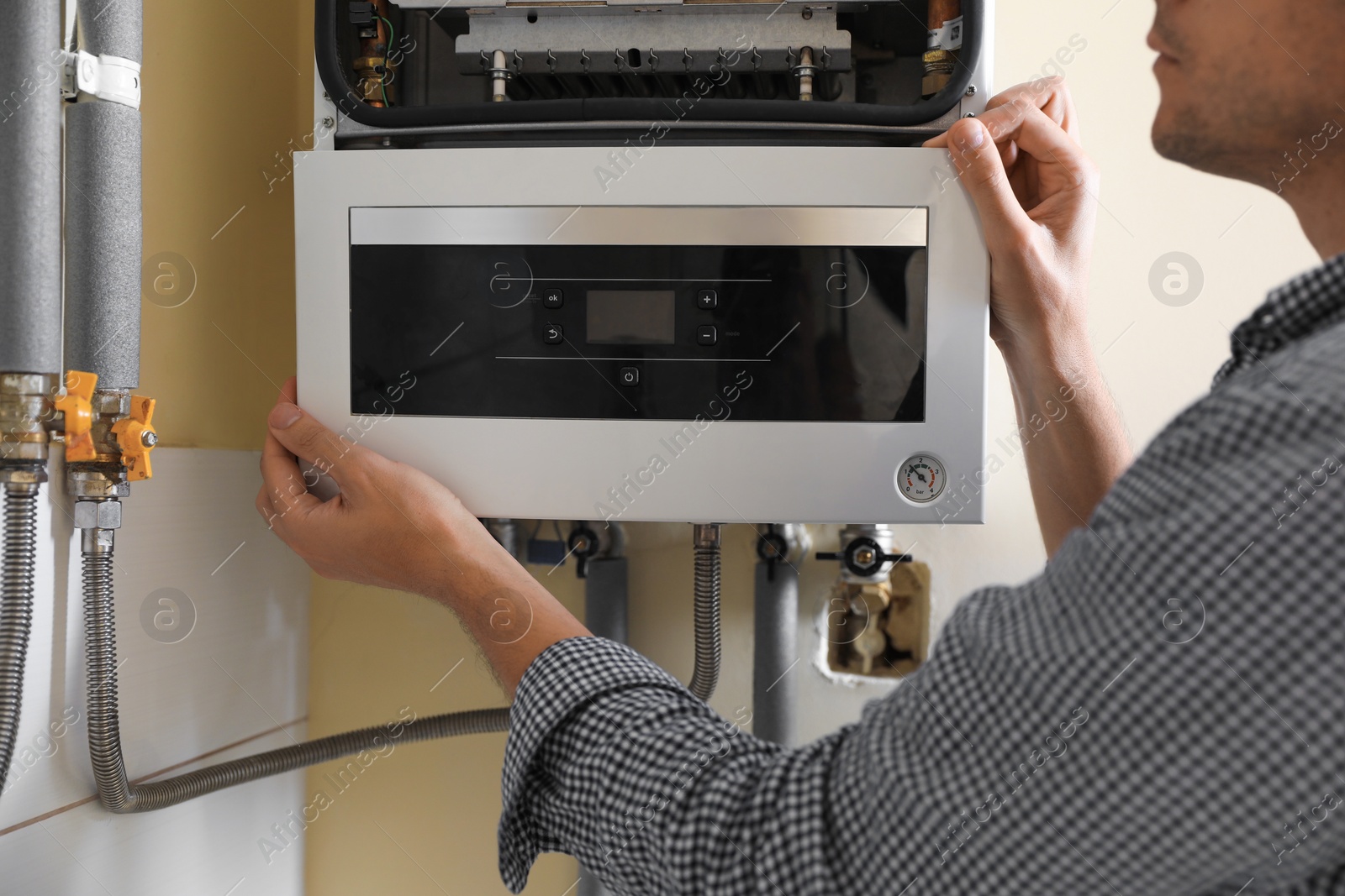 Photo of Man opening top of gas boiler indoors, closeup