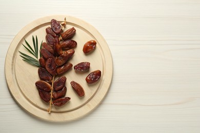 Photo of Tasty sweet dried dates on white wooden table, top view. Space for text