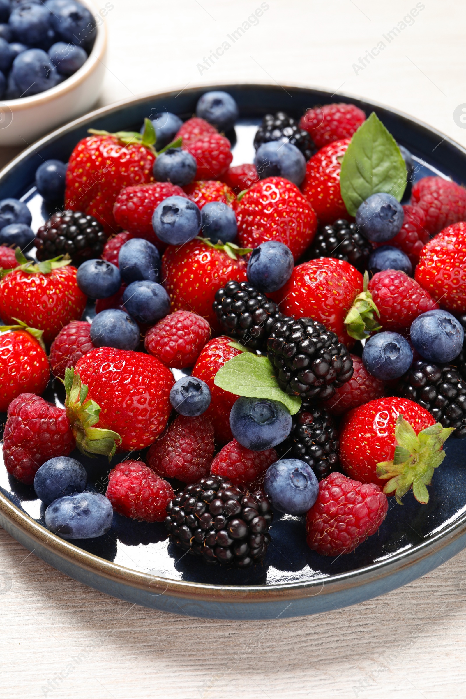 Photo of Different fresh ripe berries on light wooden table, closeup