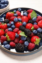 Different fresh ripe berries on light wooden table, closeup