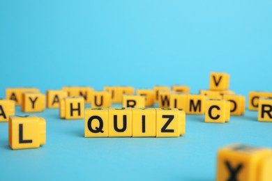 Photo of Yellow cubes with word Quiz on light blue background. Space for text