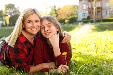 Happy mother with her daughter on green grass in park