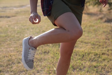 Photo of Woman applying insect repellent onto leg outdoors, closeup