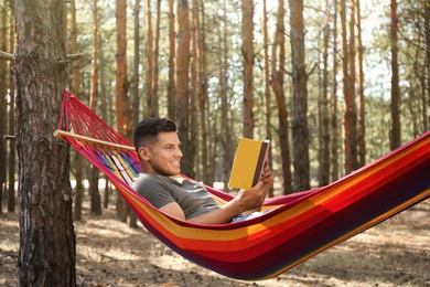 Photo of Man with book relaxing in hammock outdoors on summer day