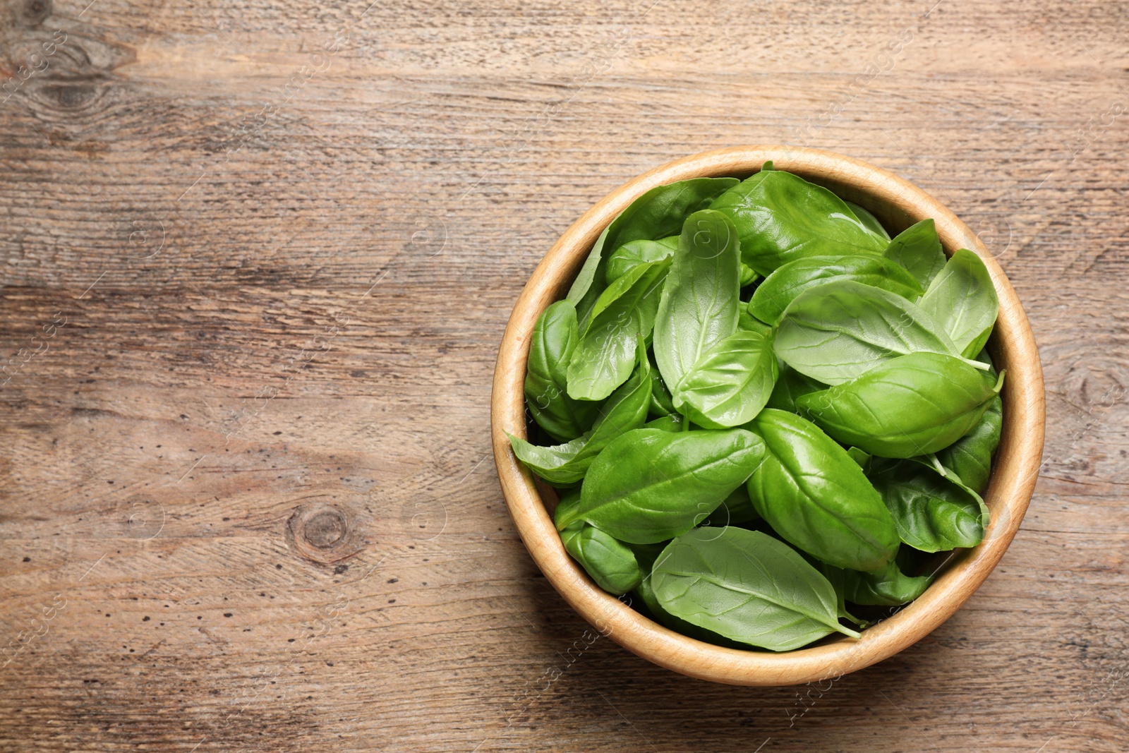 Photo of Fresh basil on wooden table, top view. Space for text