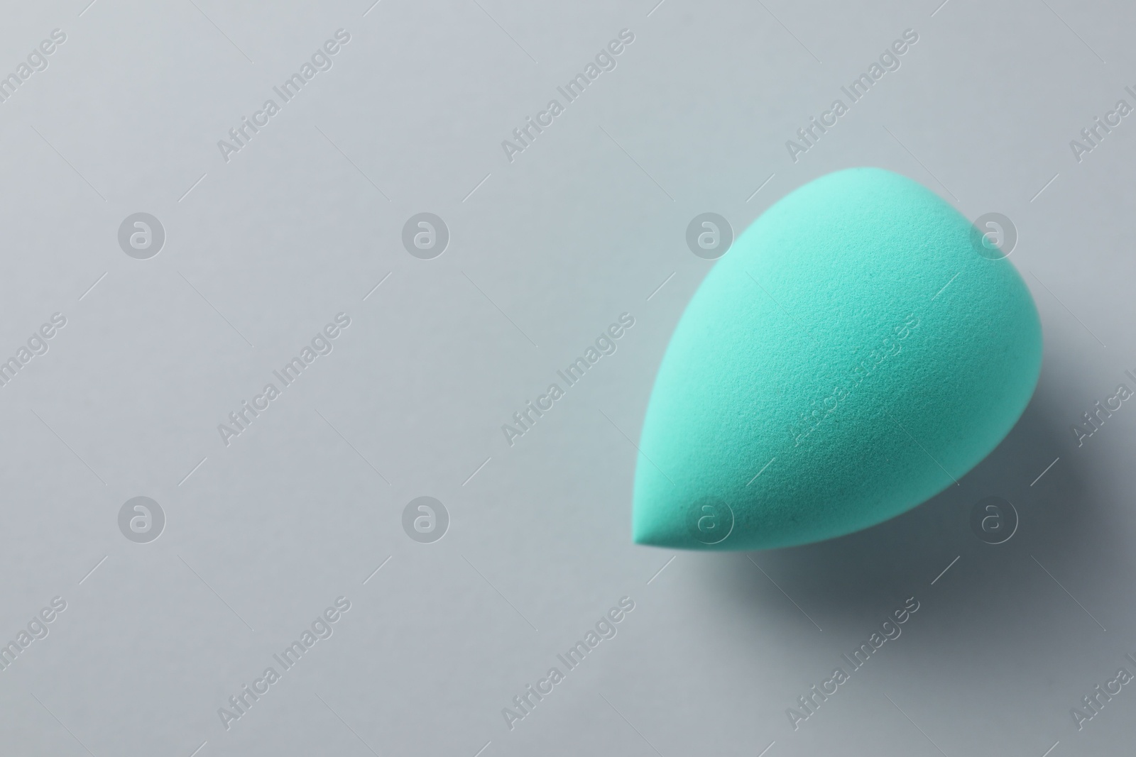 Photo of One turquoise makeup sponge on grey background, top view. Space for text