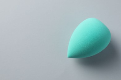 One turquoise makeup sponge on grey background, top view. Space for text