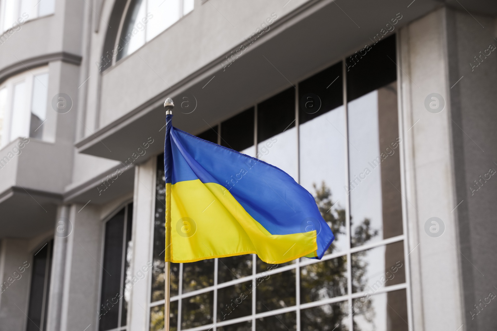 Photo of National flag of Ukraine fluttering near building on sunny day