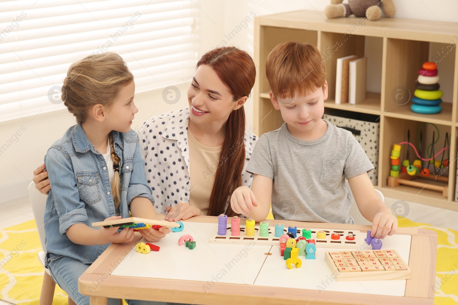 Photo of Happy mother and children playing with different math game kits at desk in room. Study mathematics with pleasure