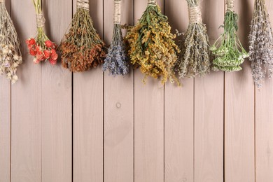 Bunches of different medicinal herbs hanging on wooden background. Space for text