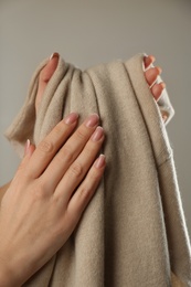 Woman with cashmere sweater on beige background, closeup