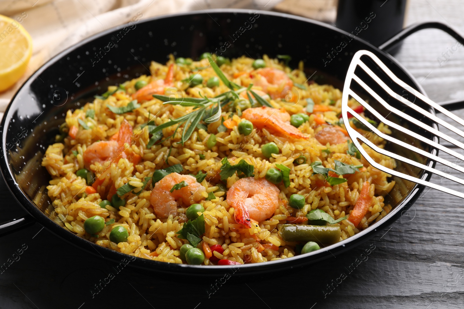 Photo of Tasty rice with shrimps and vegetables in frying pan on grey table, closeup