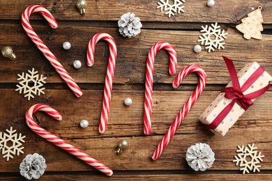 Photo of Flat lay composition with candy canes and Christmas decor on wooden background