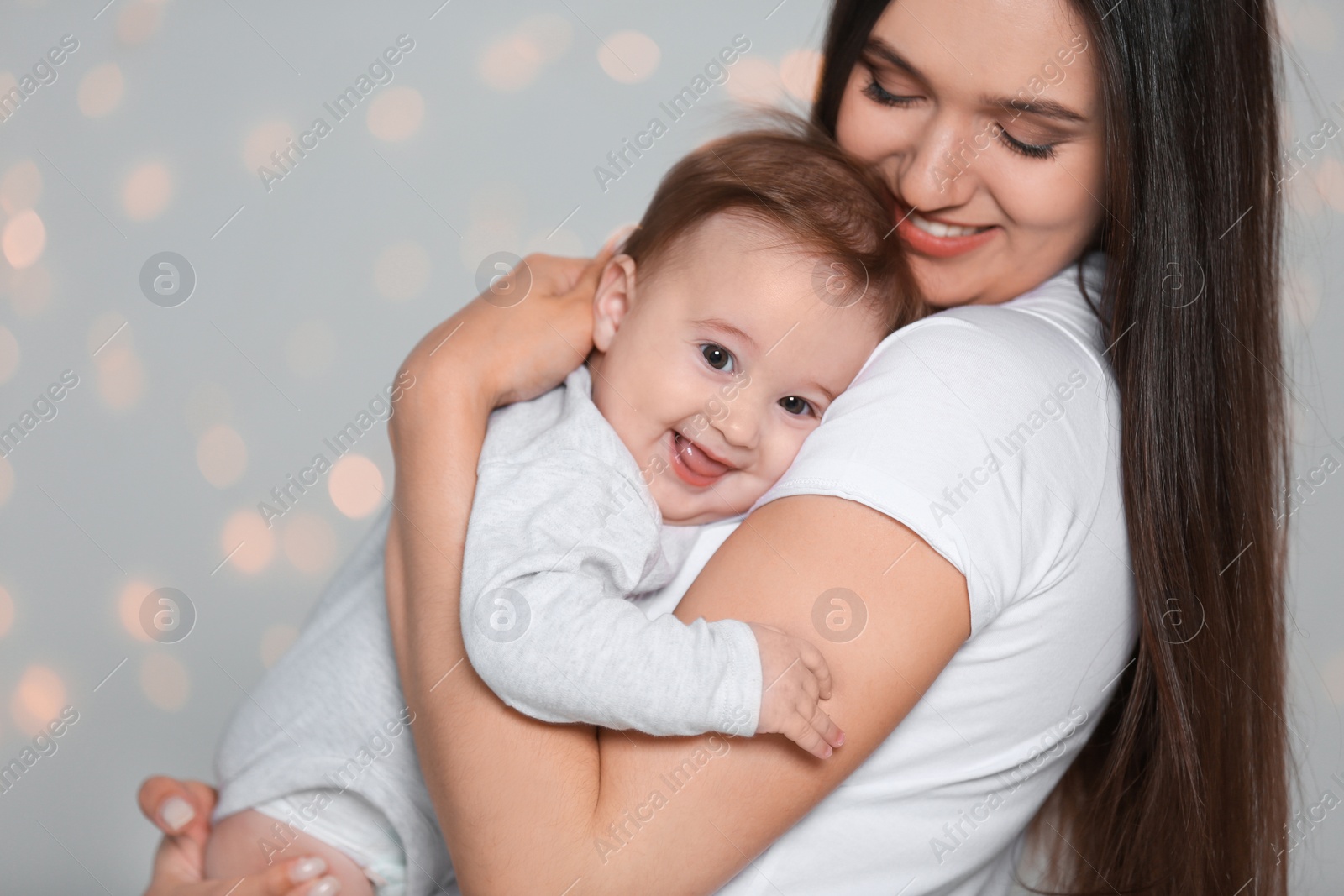 Photo of Portrait of young mother and her adorable baby against defocused lights