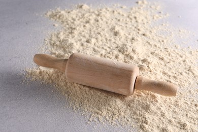 Photo of Rolling pin and scattered flour on light textured table, closeup