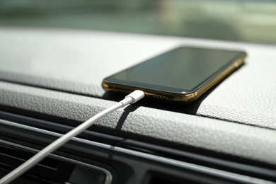 Smartphone with USB charging cable in modern car, closeup