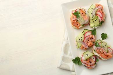 Photo of Tasty canapes with salmon served on white wooden table, top view. Space for text