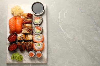 Set of tasty sushi rolls on light grey marble table, top view. Space for text