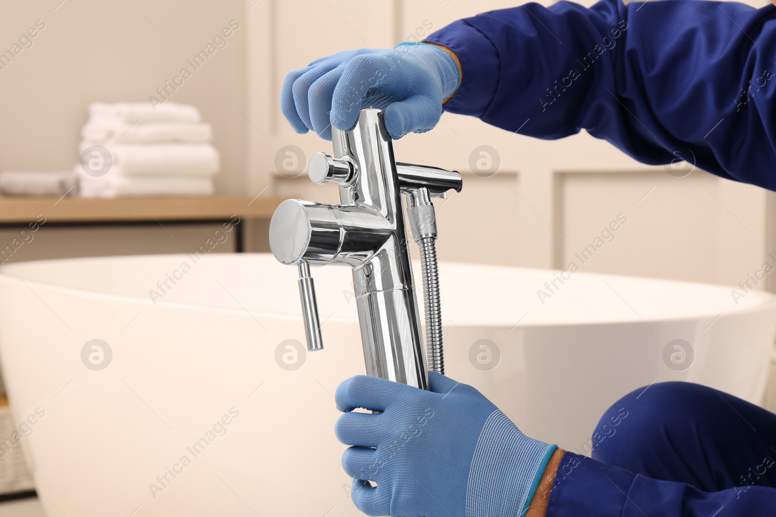 Photo of Professional plumber installing water tap in bathroom, closeup