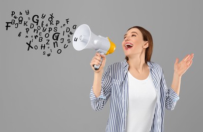 Woman using megaphone on grey background. Letters flying out of device