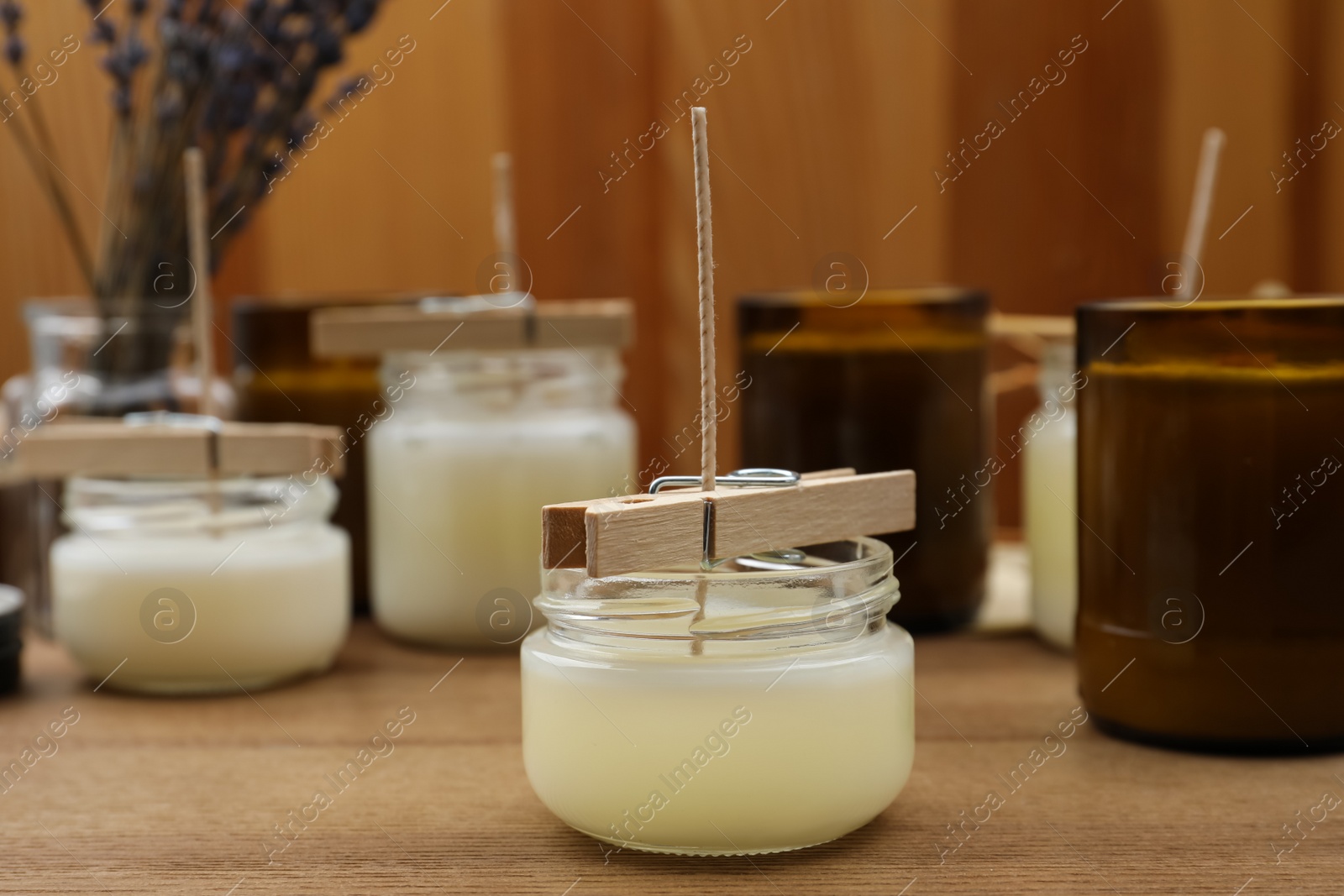 Photo of Glass jars with wax on wooden table. Handmade candles