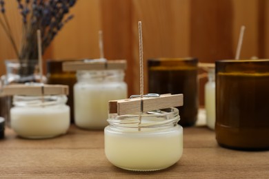 Photo of Glass jars with wax on wooden table. Handmade candles