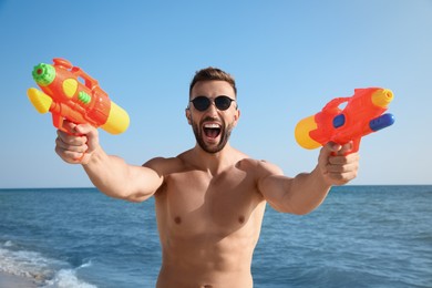 Photo of Man with water guns having fun on beach