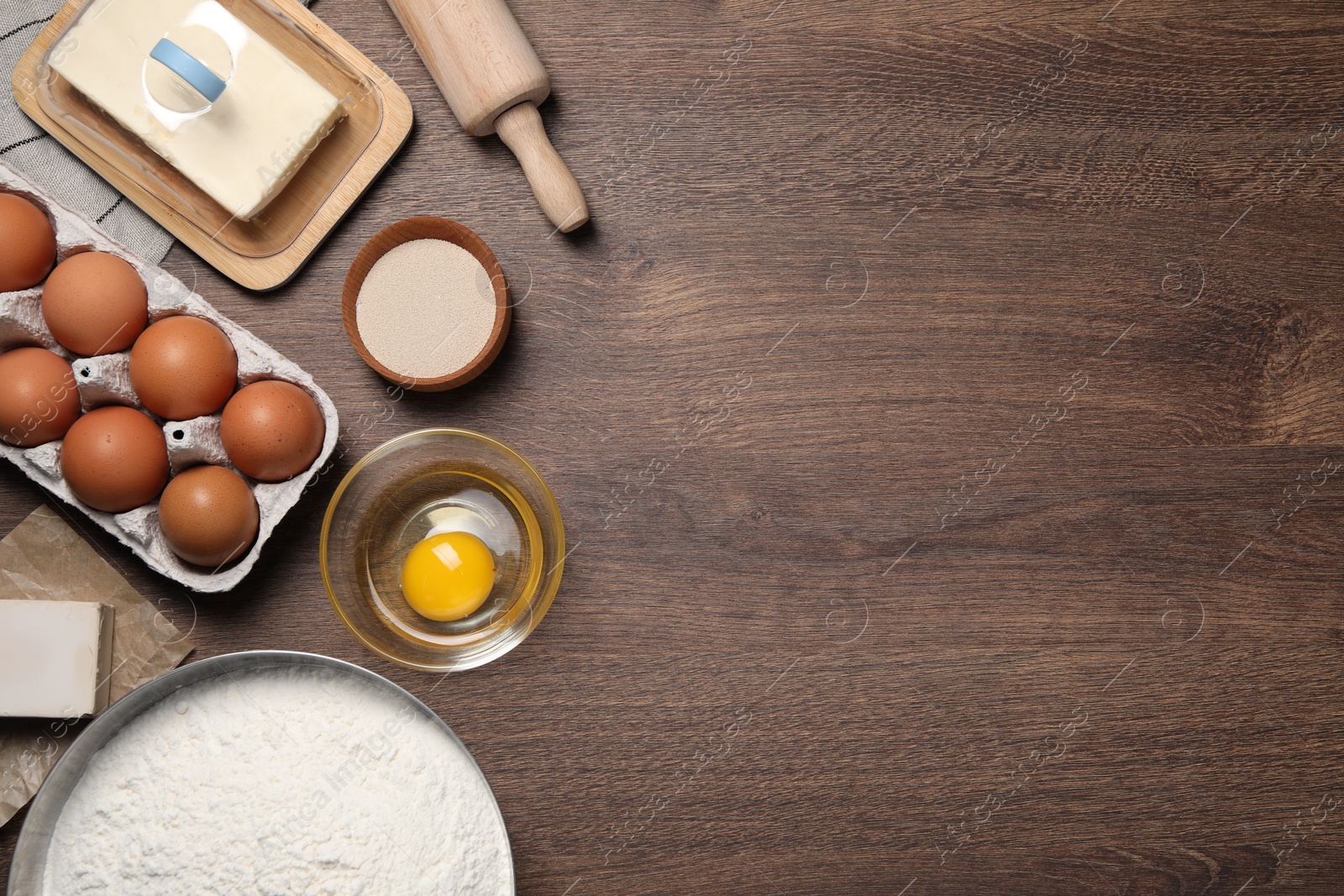 Photo of Flat lay composition with flour, eggs and ingredients on wooden table, space for text. Cooking yeast cake