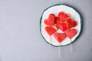 Plate with watermelon popsicles on grey background, top view