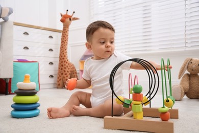 Photo of Cute baby boy playing with toys on floor at home