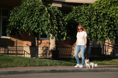 Woman walking with her cute Chihuahua dog on sidewalk outdoors