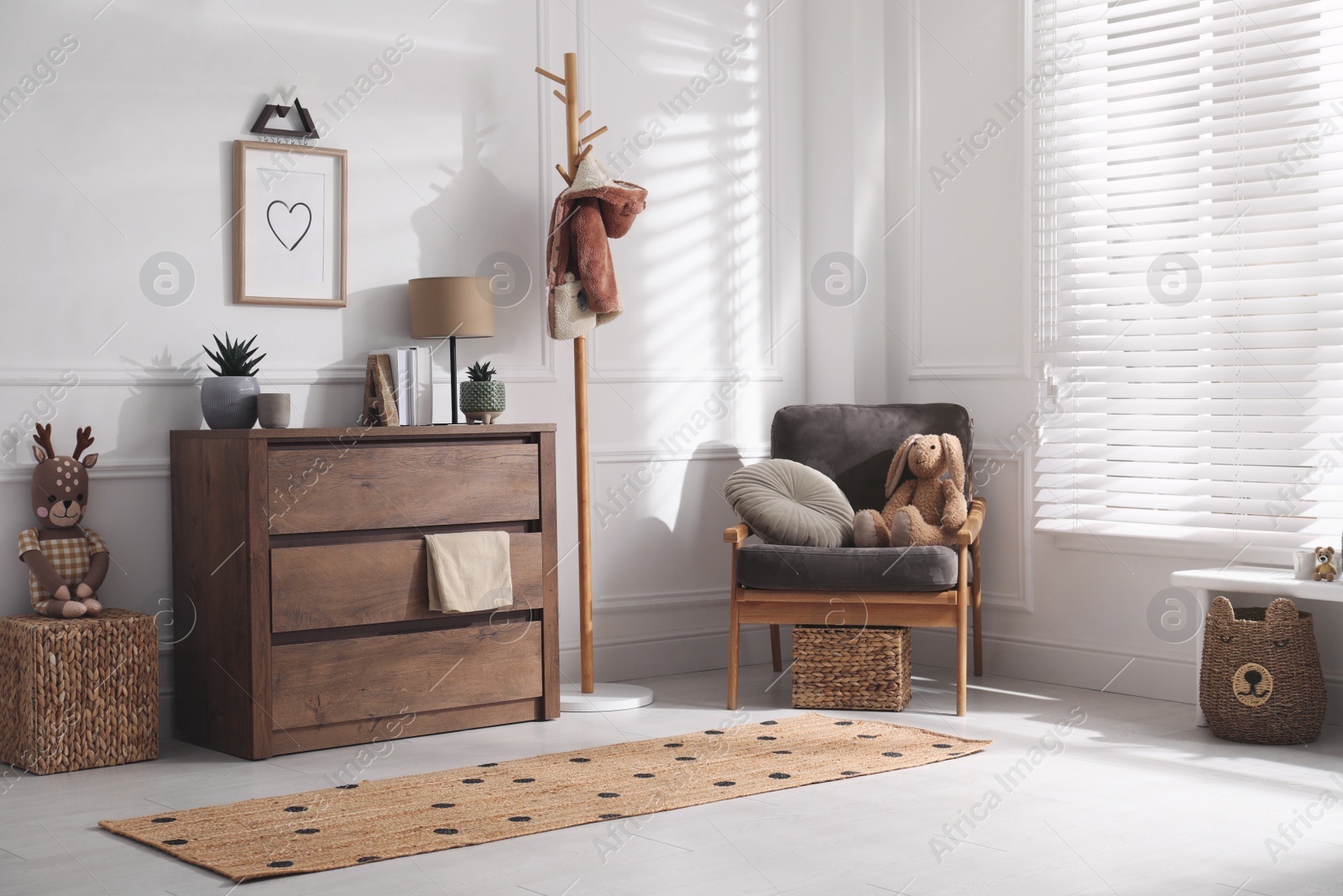 Photo of Stylish room interior with wooden chest of drawers and comfortable armchair