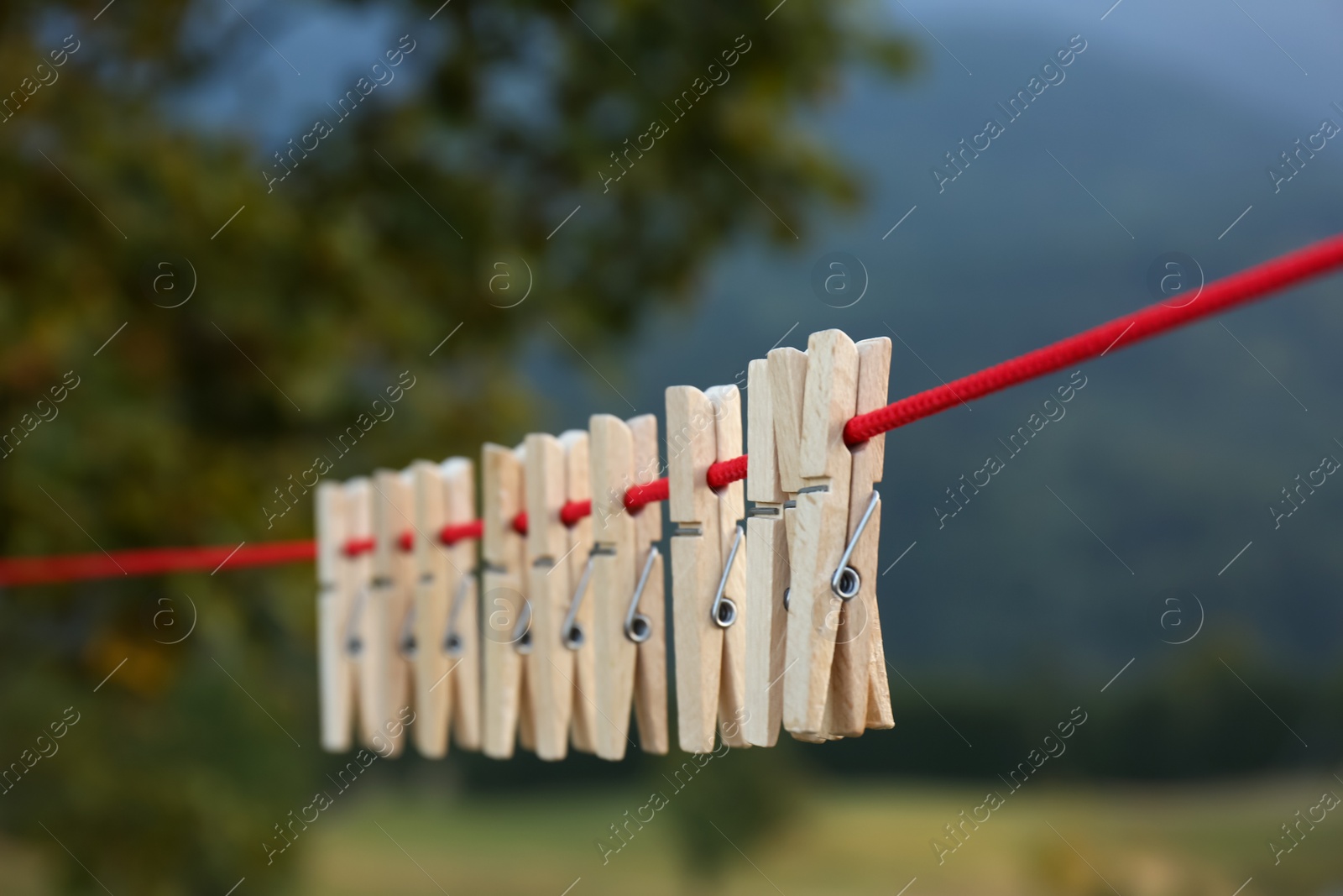 Photo of Wooden clothespins hanging on washing line outdoors