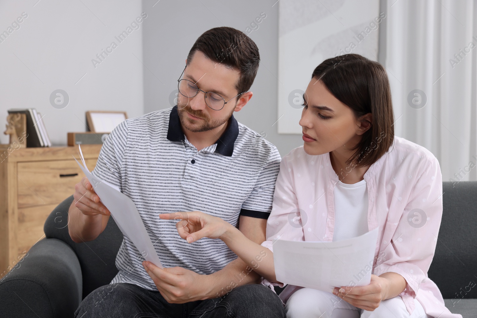 Photo of Young couple with papers discussing pension plan indoors